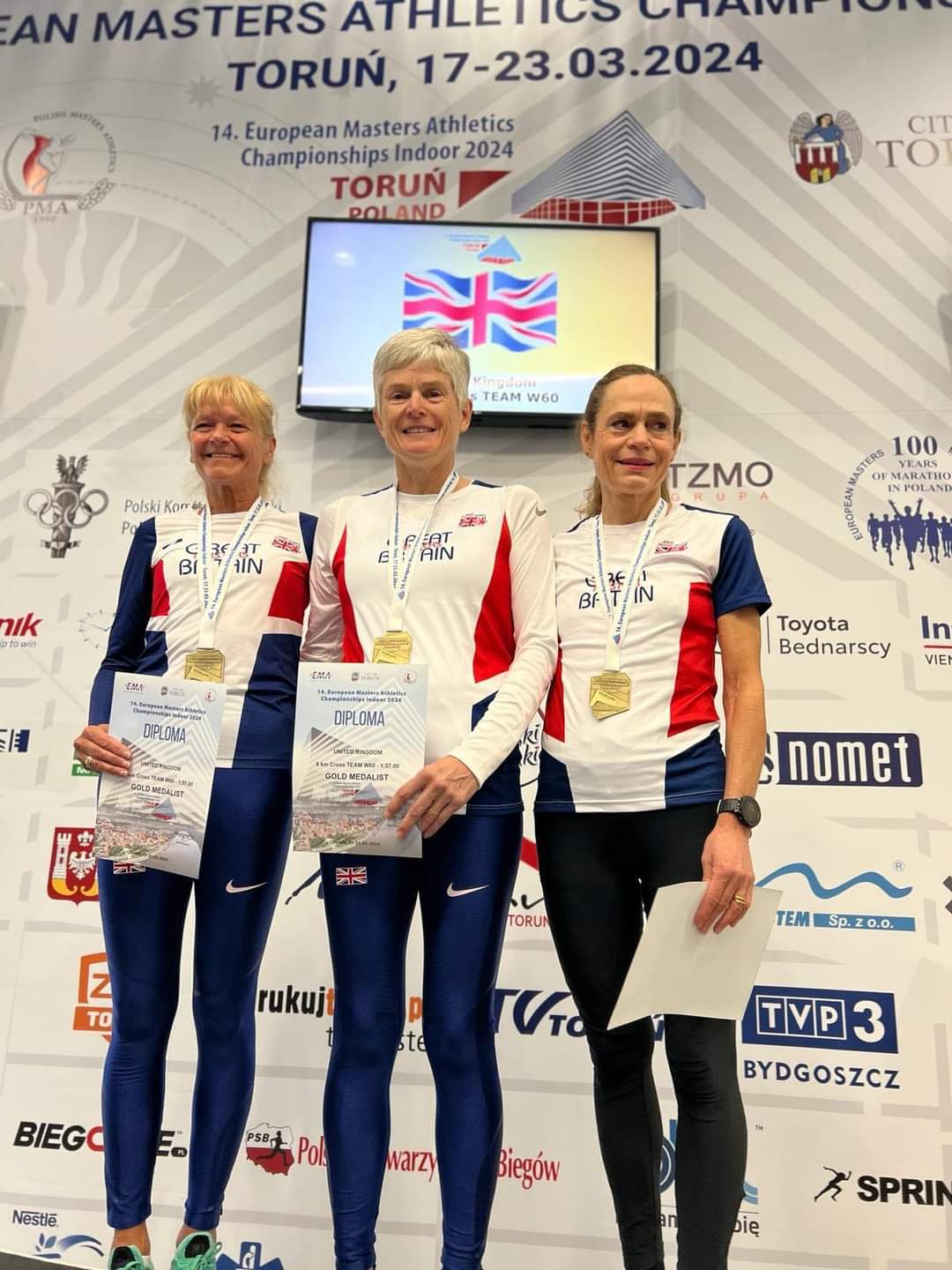 Three runners standing on a podium in  their GB kit